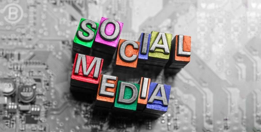 Colorful blocks with letters spelling "SOCIAL MEDIA" placed on a grey circuit board background, showcasing a modern social media design.